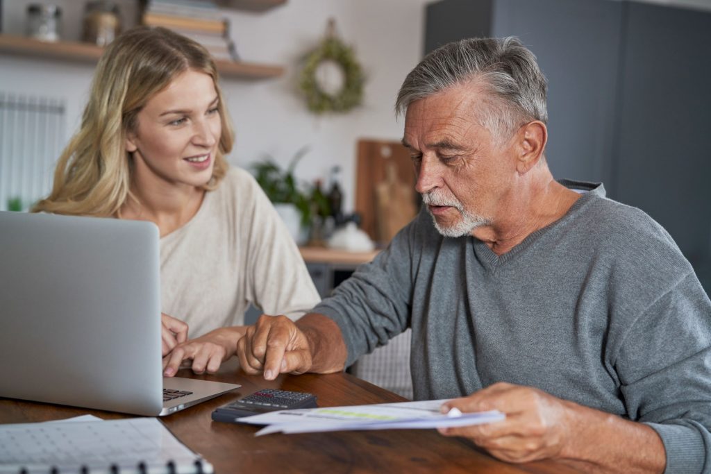 Senior man with adult daughter at a table with a computer - Medicaid Planning and Long-Term Care