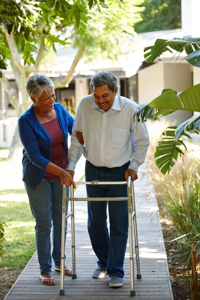 Senor woman helping her husband who is walking with walker - Medicaid Planning and Long-Term Care